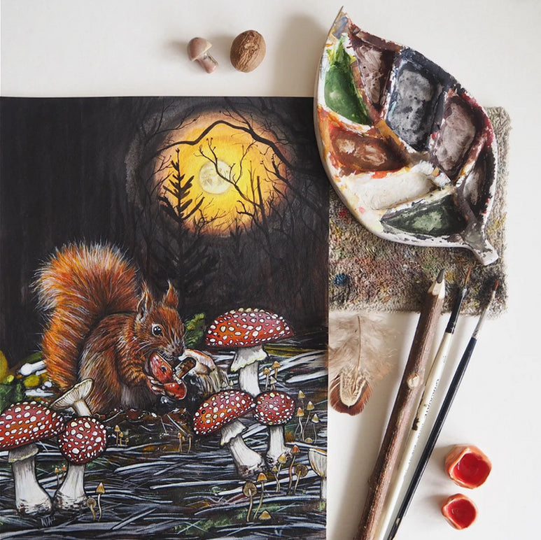 A painting of a red squirrel eating toadstool mushrooms under the full moon, surrounded by a homemade leaf palette and brushes. 